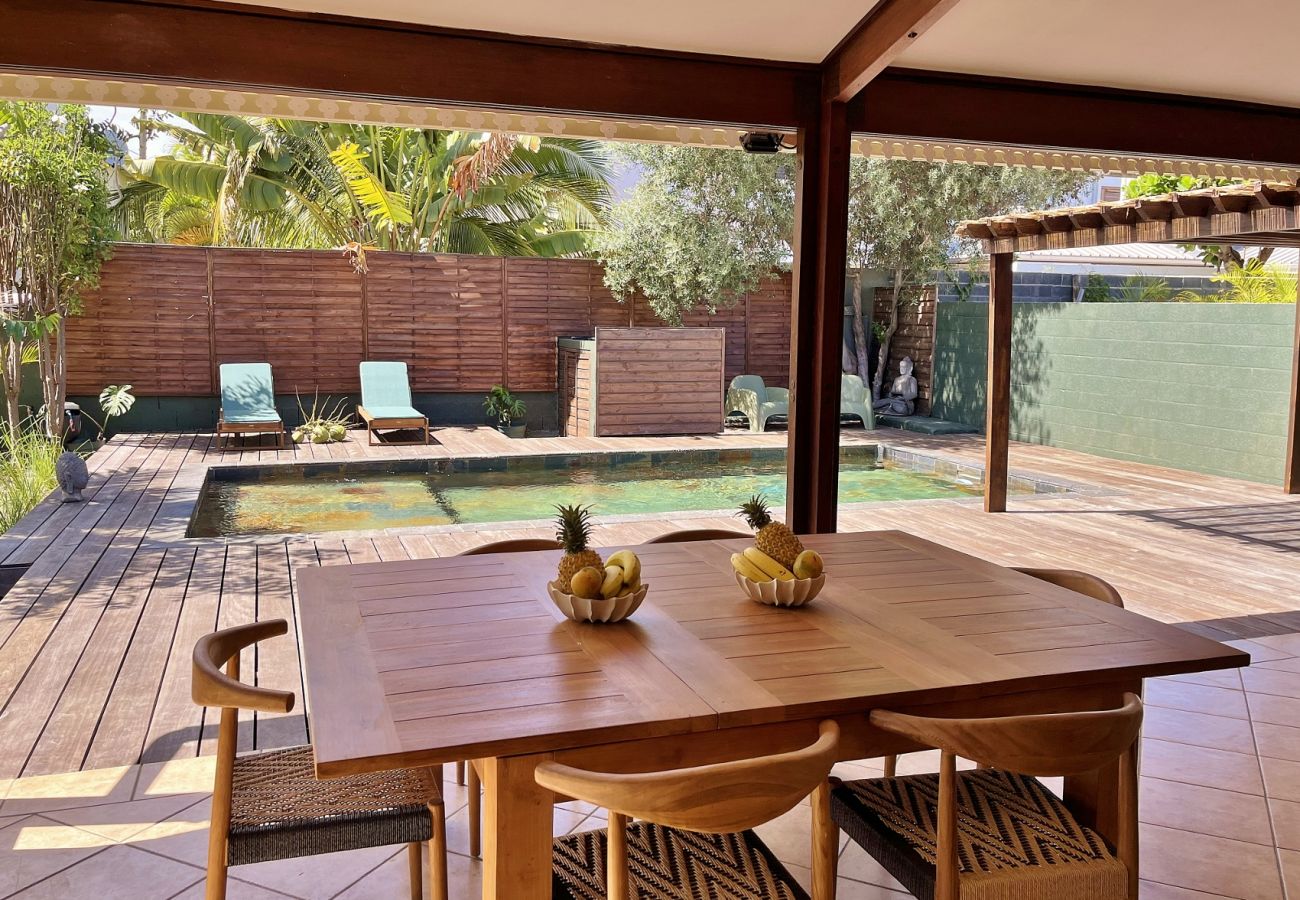 Wooden dining table under covered veranda overlooking Villa des Parfums pool